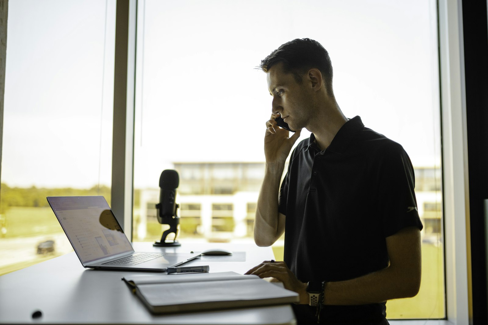 Ofis masasında telefonla görüşme yapan bir kişi ve önünde açık duran not defteri